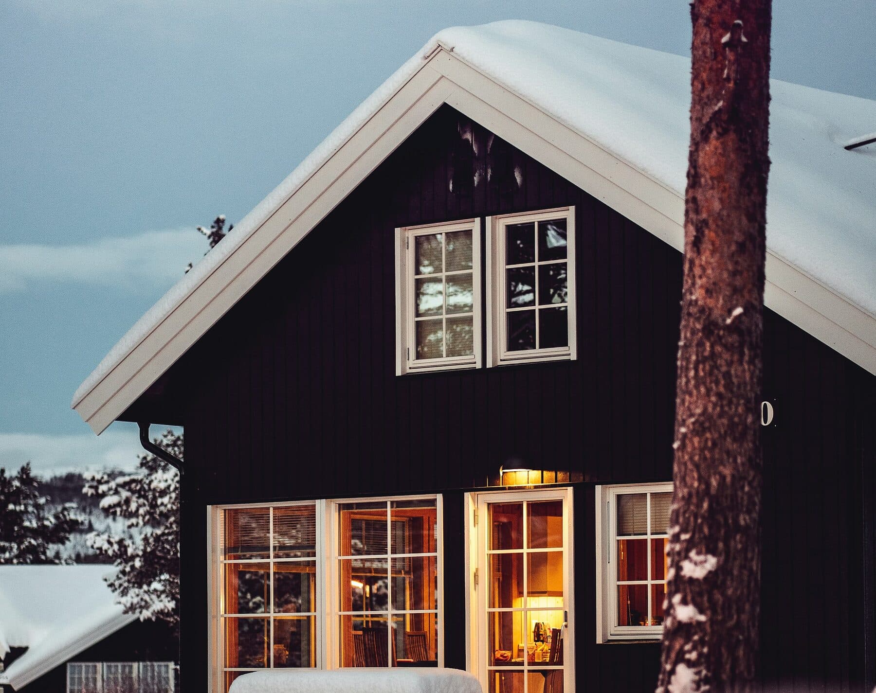 Norsk trehus i skumringen med lys i vinduene